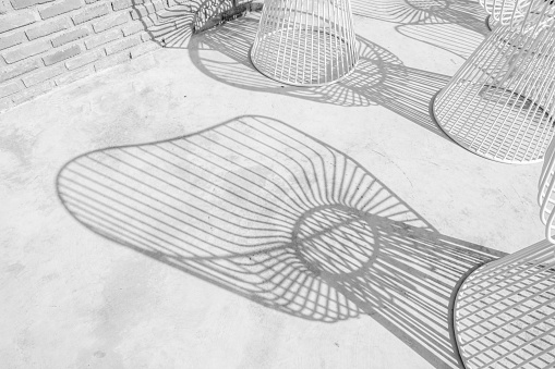 abstract backgrounds shadow of steel rod outdoor-chairs lay beautifully & looks dimension over light gray concrete flooring under beneath the warm sunlight of day