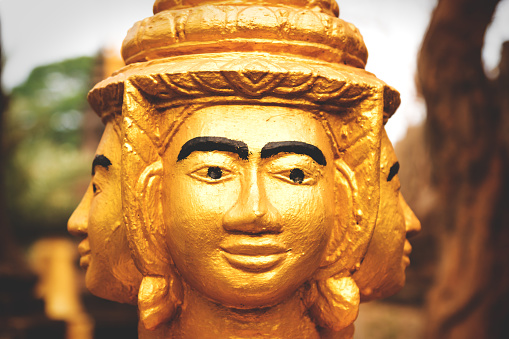 Three heads of orange golden Buddha statue in monesary in Siem Reap, Cambodia