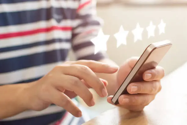 Photo of Customer service experience and business satisfaction survey. Close-up image of male hands using mobile smart phone with icon five star symbol to increase rating of company concept