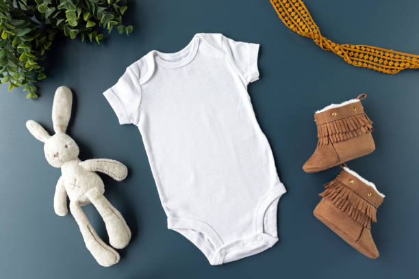 gender neutral blank white baby body flat lay mockup with blue background - baby clothing mock up - styled stock photography - onesie foto e immagini stock