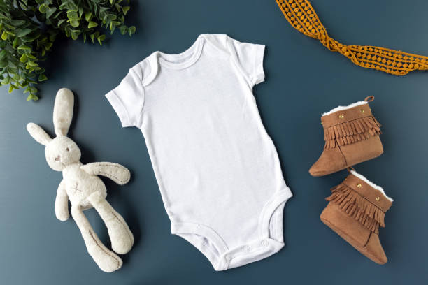 Gender Neutral Blank White Baby Bodysuit Flat lay Mockup With Blue Background - Baby Clothing Mock Up - Styled Stock Photography Baby Clothing Mockup babygro stock pictures, royalty-free photos & images