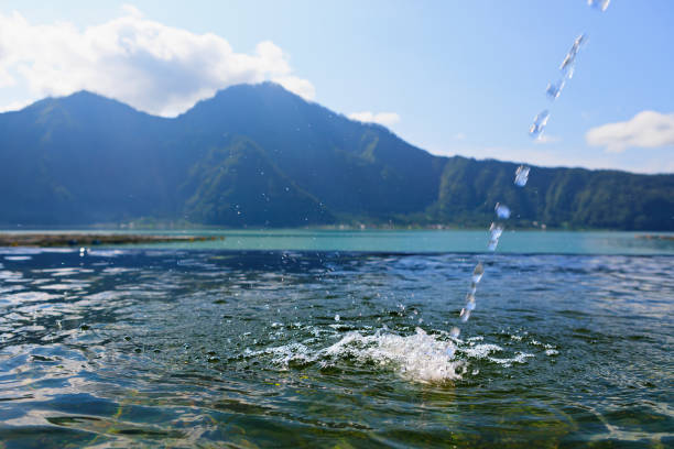 Natural hot spring spa beside Batur volcano. Hot water flowing to infinity pool with beautiful lake and mountain Abang view. Popular travel destination on family summer holiday in Kintamani, Bali.
