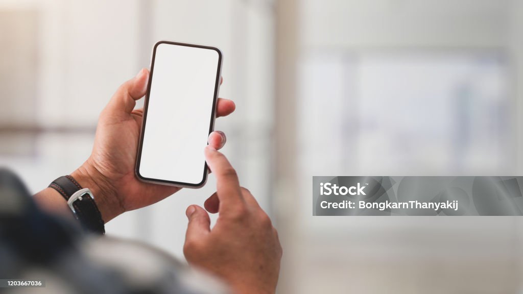 Close up view of a man using blank screen smartphone Close up view of a man using blank screen smartphone while working in office room Telephone Stock Photo Close up view of a man using blank screen smartphone Close up view of a man using blank screen smartphone while working in office room Telephone Stock Photo