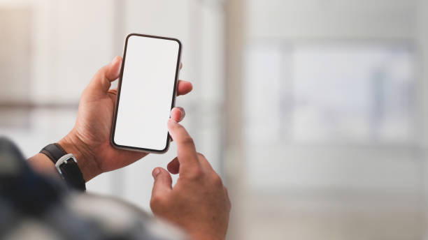 Close up view of a man using blank screen smartphone Close up view of a man using blank screen smartphone while working in office room hand holding phone screen stock pictures, royalty-free photos & images