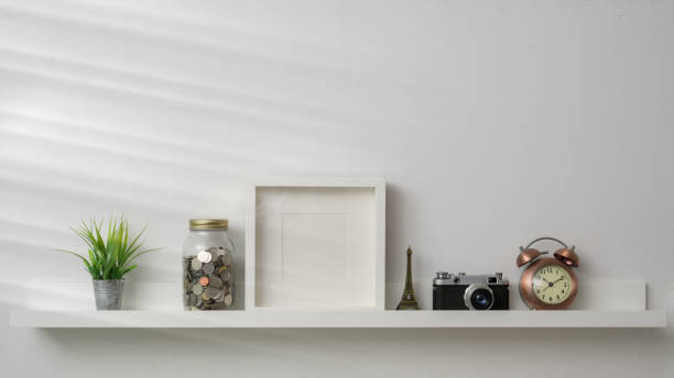 istock Cropped shot of mock up frame, camera and decorations on white shelf with white wall background 1203667091
