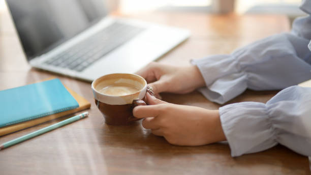 istock Side view of a woman holding coffee cup  in comfortable workplace 1203671023