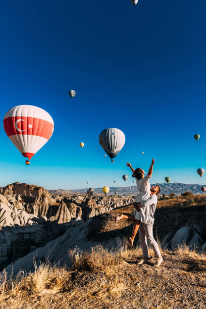 Honeymoon trip. Couple in love among balloons. A man proposes to a girl. Couple in love in Cappadocia. Couple in Turkey.  Man and woman traveling. Festival of balloons. The couple travels the world stock photo