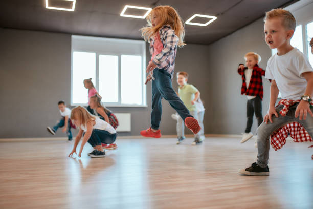 istock Getting higher. Children jumping while having a choreography class. Group of cute little boys and girls studying modern dance in studio 1203680305
