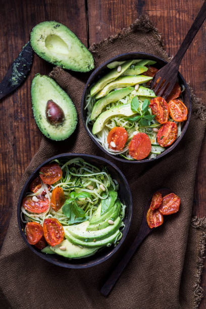 ensalada saludable con fideos de calabacín zoodles, tomates asados al horno y aguacate - antiinflamatorio fotografías e imágenes de stock