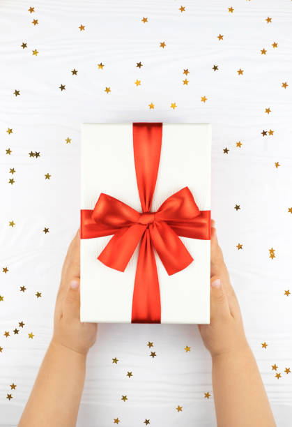 istock Child's hands holding gift box on white background. 1203680500