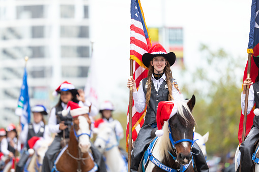Houston, Texas, USA - November 28, 2019: H-E-B Thanksgiving Day Parade, Group of Mounted Police Officers riding horses, waving at people during the parade