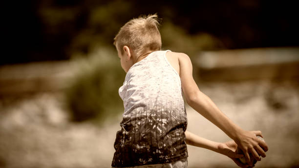 garotinho em pé e jogando uma pedra no rio - throwing stone little boys child - fotografias e filmes do acervo