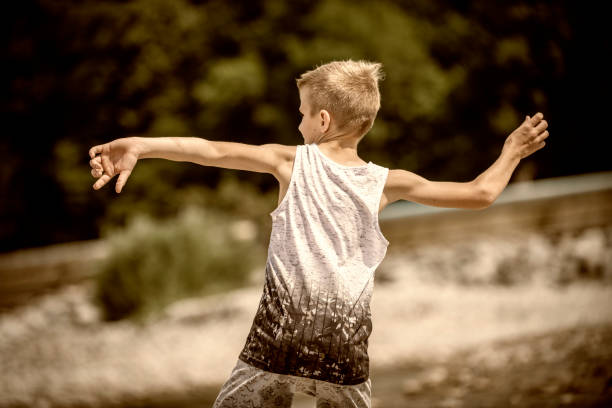 mały chłopiec stojący i rzucający kamieniami do rzeki - throwing stone little boys child zdjęcia i obrazy z banku zdjęć