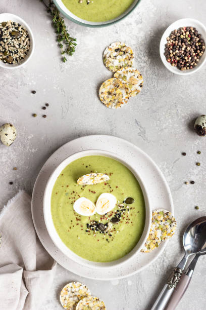 istock Detox broccoli green cream soup with seed mix, quail egg and crackers in bowl on light grey stone background. Top view. Healthy food concept. 1203688749