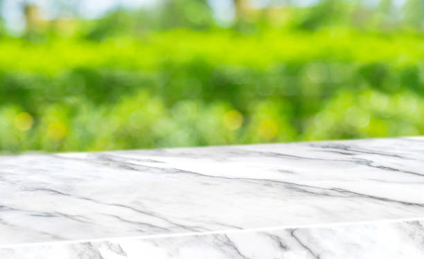 istock spring background.Empty diagonal white marble table with blur tree in garden boekh background,banner mockup template for display of product 1203689787