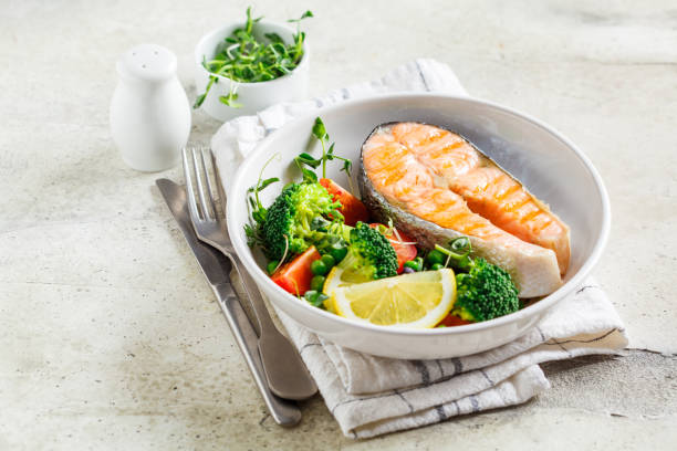 istock Grilled salmon steak with broccoli and tomatoes in white plate on gray background, copy space. Diet food concept. 1203696292