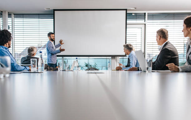 istock Happy CEO giving a business presentation through projection screen in a board room. 1203697687