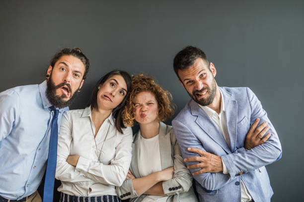 istock Team of young business people making faces against gray wall. 1203698655