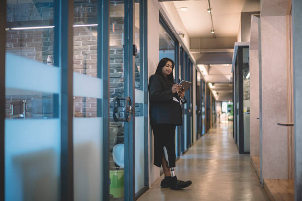 istock an asian indian female handicapped white collar worker with prosthetic limb  checking on her digital tablet in the office corridor 1203703353