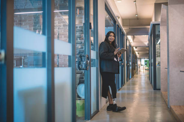 istock an asian indian female handicapped white collar worker with prosthetic limb  checking on her digital tablet in the office corridor 1203703376
