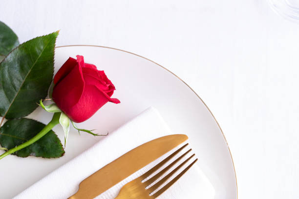 istock Red rose on white plate with gold cutlery. Saint valentines day celebration or romantic dinner concept.Close up 1203705352