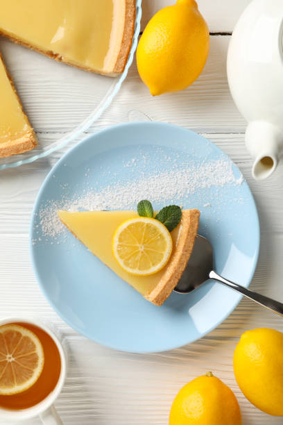 istock Composition with lemon tart slice on plate on white wood background, top view 1203707866