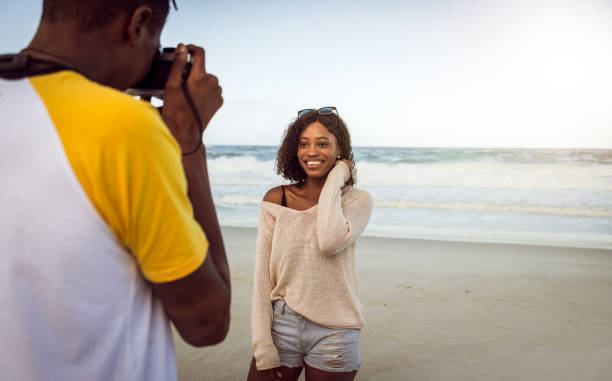 istock Young Man Photographing His Girlfriend On The Beach 1203708830