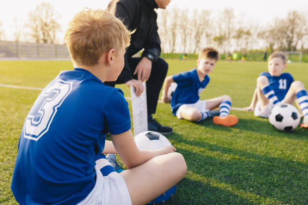 young soccer trainer coach erklärt taktik auf team sports tactics board. kinder während der fußball-coaching-session. jungen im fußballteam hören dem trainer zu - sports uniform blue team event sports activity stock-fotos und bilder