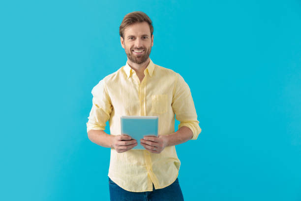 istock Happy casual man holding a tablet and looking forward 1203710831