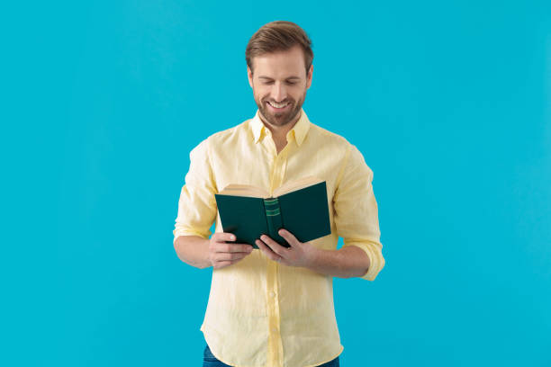 istock Happy casual man reading a book and smiling 1203711866
