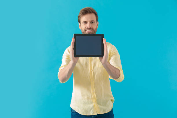 istock Positive casual man showing and presenting his tablet 1203712249
