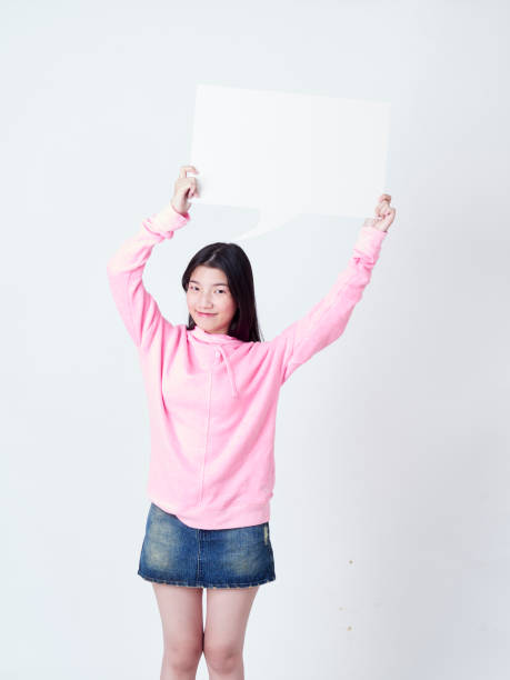 istock Cheerful girl smiling at camera and showing placard empty. 1203712764