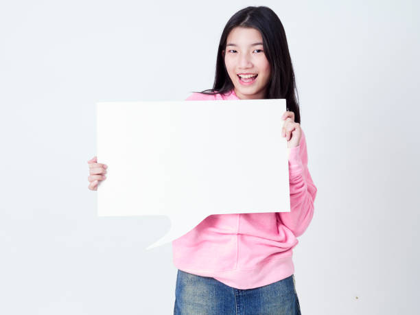 istock Cheerful girl smiling at camera and showing placard empty. 1203712772