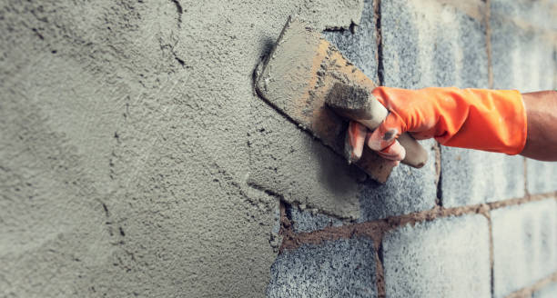 istock close up hand worker plastering cement on wall for building house 1203713429