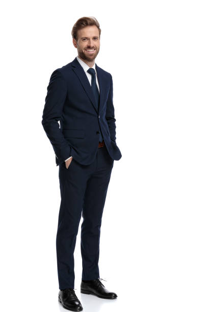 happy young businessman holding hands in pockets and smiling - mans suit imagens e fotografias de stock