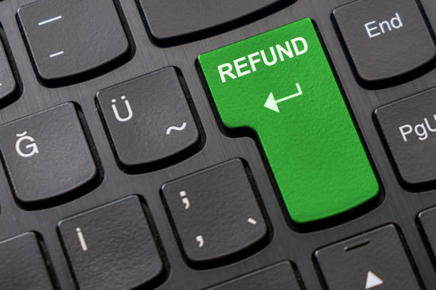 Green "refund" key on the black computer keyboard. stock photo