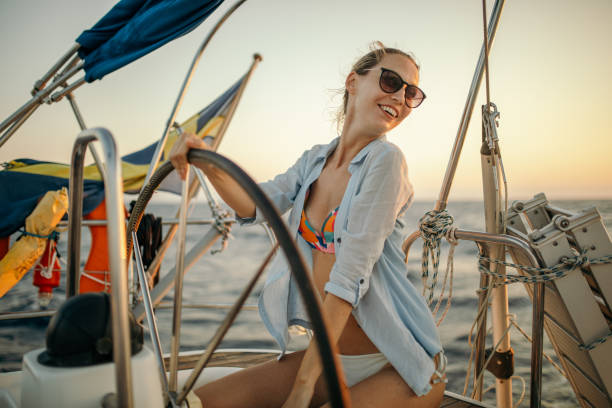 istock Woman on sailboat steering at sunset 1203716651