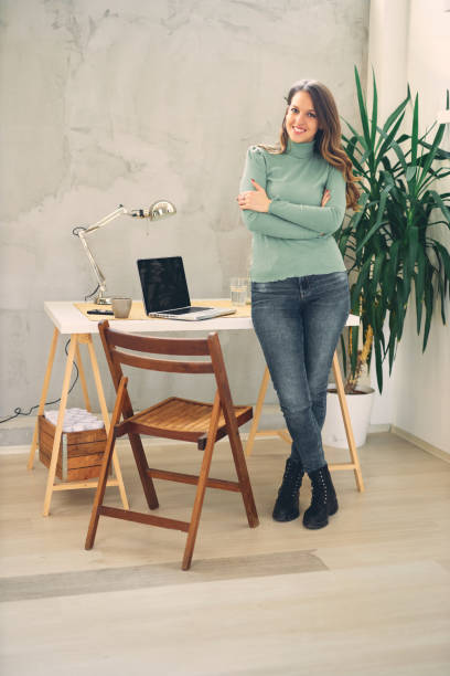 istock Young attractive female standing in modern office and looking at camera. 1203717440