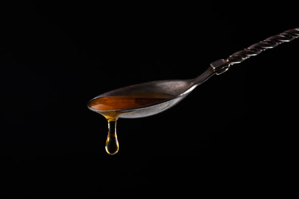 istock honey pours from a vintage silver spoon on a black background close-up 1203719021