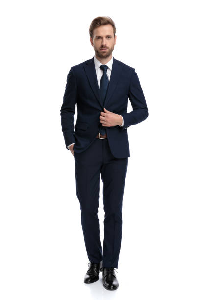 young businessman in navy blue suit adjusting coat young businessman in navy blue suit adjusting coat and walking isolated on white background, full body necktie fashion adjusting suit stock pictures, royalty-free photos & images