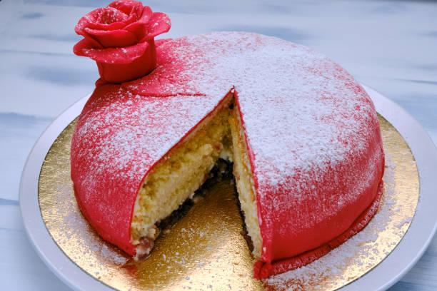 istock Red cake covered with marzipan or mastic with a cut piece, close-up 1203720423