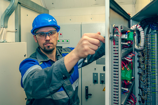 Energy and electricity, electromechanical protective at work with an electric panel, an electrician diagnoses electrical distribution panels in an electrical panel, toned