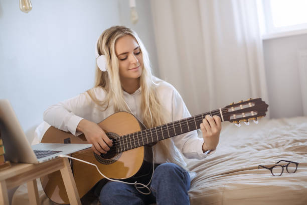 istock Gir Learning to Play Guitar at Home 1203720844