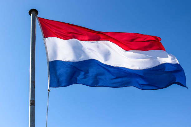 istock Dutch flag on a flagpole waving in the wind, close up on a blue sky background 1203723615