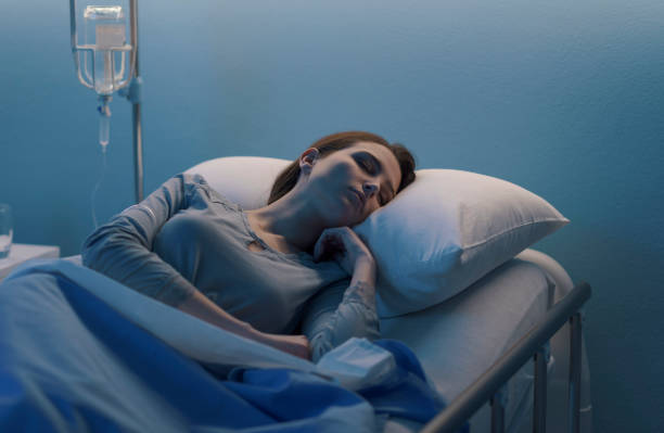 Woman lying in the hospital bed and sleeping with IV drip Young woman lying in a hospital bed at night and sleeping with IV drip night hospital bed stock pictures, royalty-free photos & images