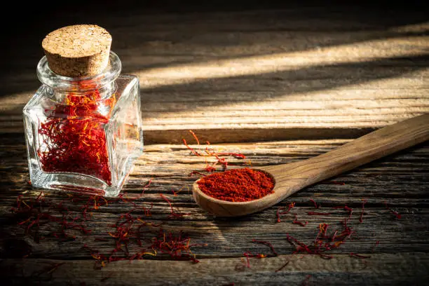 Saffron spice in glass bottle on rustic wooden table background