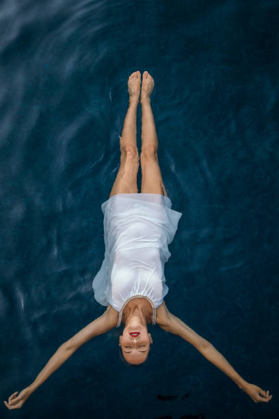 jeune femme dans la robe flottant sur l'eau - floating on water water women wet photos et images de collection