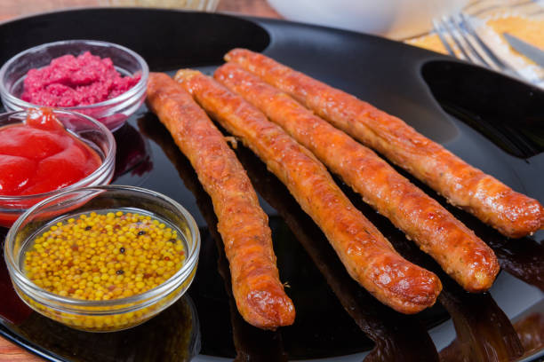 istock Grilled pork sausages with condiments on black dish close-up 1203725930