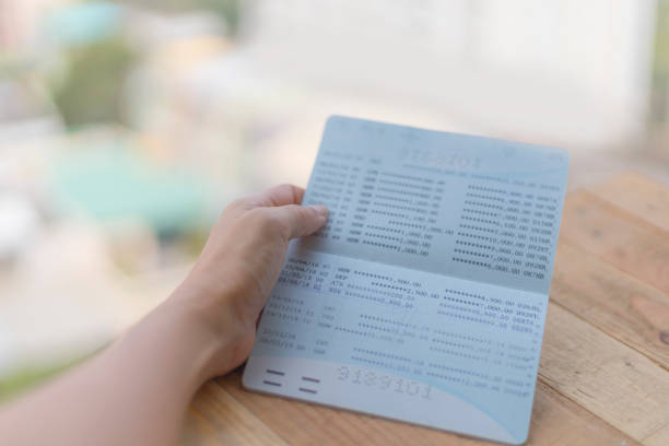 istock Hands open passbook for checking balance of statement on wood background 1203726953