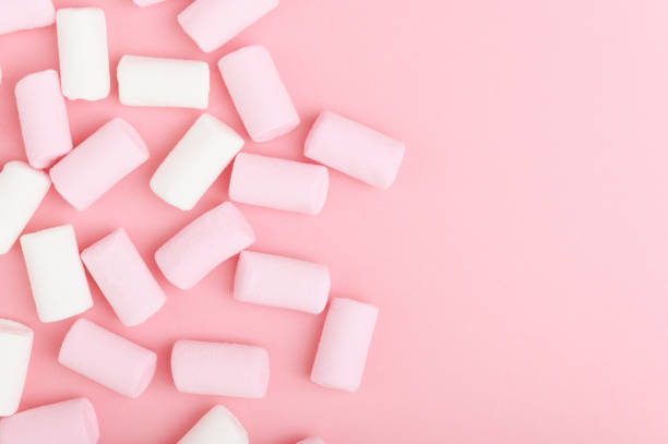 um monte de marshmallow branco e rosa em um fundo de luz pastel. doces coloridos e insalubres vistas de cima. doces de açúcar de pano de fundo rosa com espaço de cópia - unhealthy eating copy space marshmallow softness - fotografias e filmes do acervo